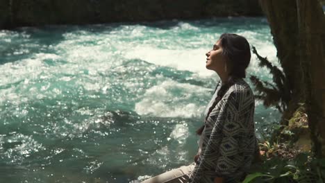 woman relaxing by a mountain river