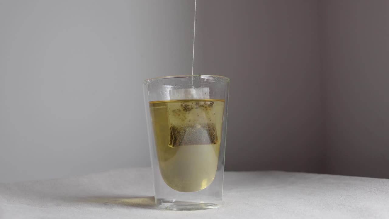 Bustina di tè che si immerge nell'acqua calda in un bicchiere