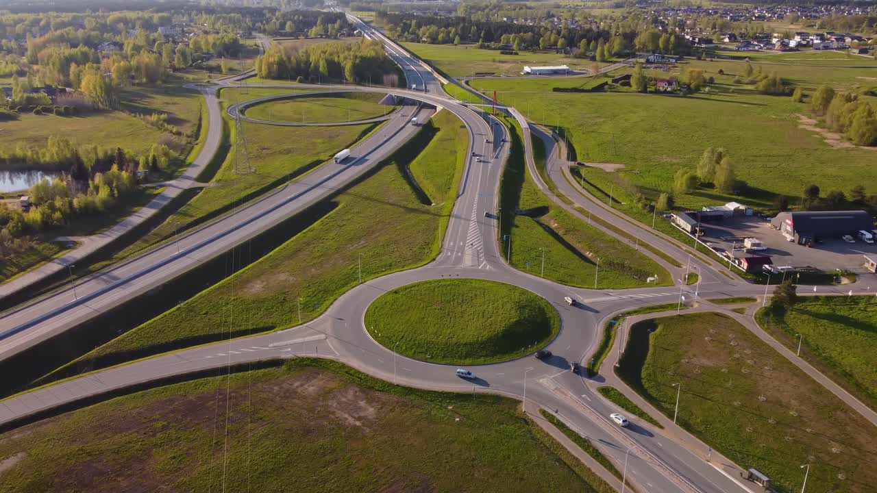 Sweeping aerial of springtime traffic roundabout and nearby residential structures, drone angled approach