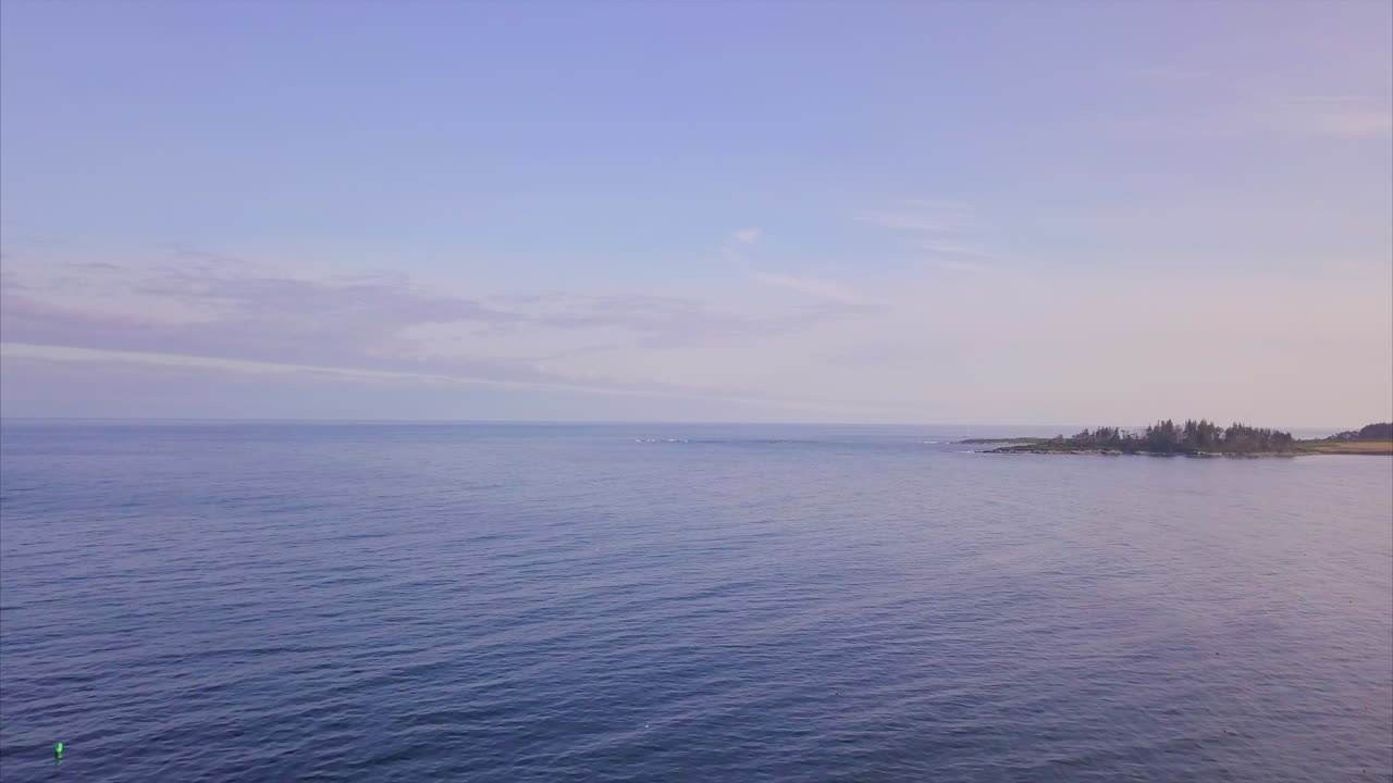 멀리 있는 작은 섬 해변과 위의 푸른 흐린 하늘이 있는 광대한 깊고 푸른 바다 위로 날아가는 공중 샷