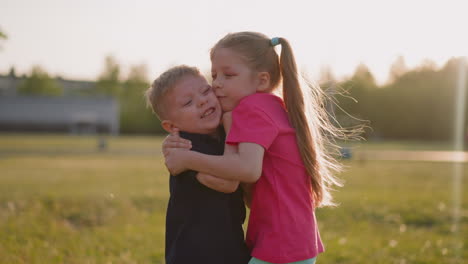 little children hug on green meadow at sunset light