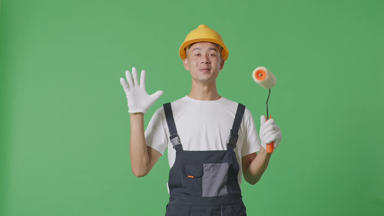 Asian Man Painter Wearing Safety Helmet Smiling And Saying Wow While Standing In The Green Screen Background Studio