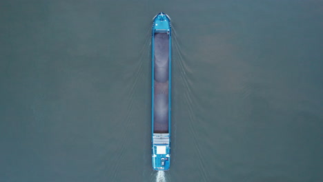 Above-drone-shot-of-an-empty-cargo-ship-traveling-upstream-on-the-river-Amer,-Netherlands