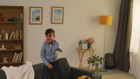 Disruptive-Young-Boy-Behaving-Badly-At-Home-Jumping-On-Sofa-And-Throwing-Cushions-Around-Lounge-3