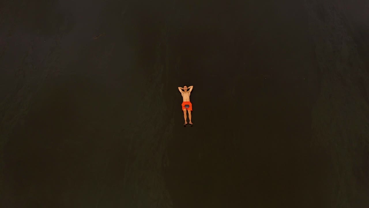 공중은 텅 빈 검은 모래 해변에 누워 있는 청년 위로 로켓처럼 날아간다