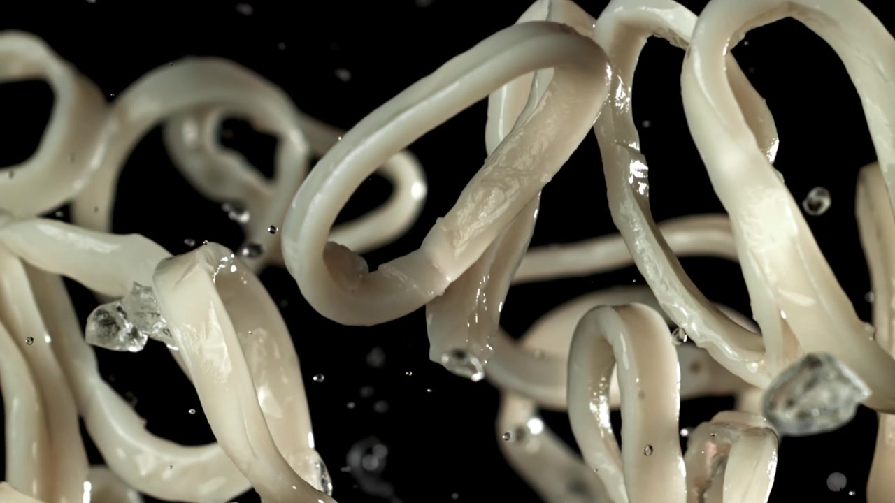 Anelli di calamari che cadono con schizzi d'acqua su sfondo nero, al rallentatore