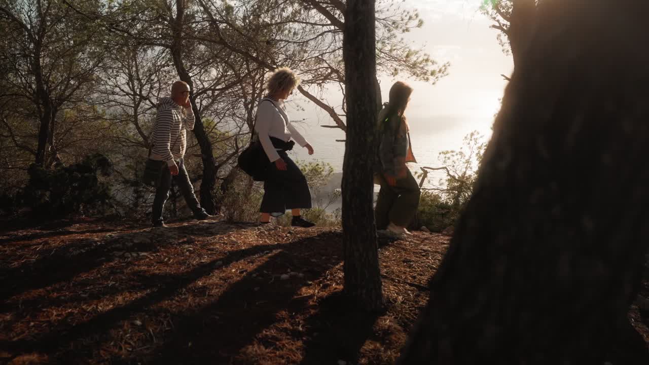 Group of friends walking in the forest in a cliff with sea views, evening sunset lifestyle