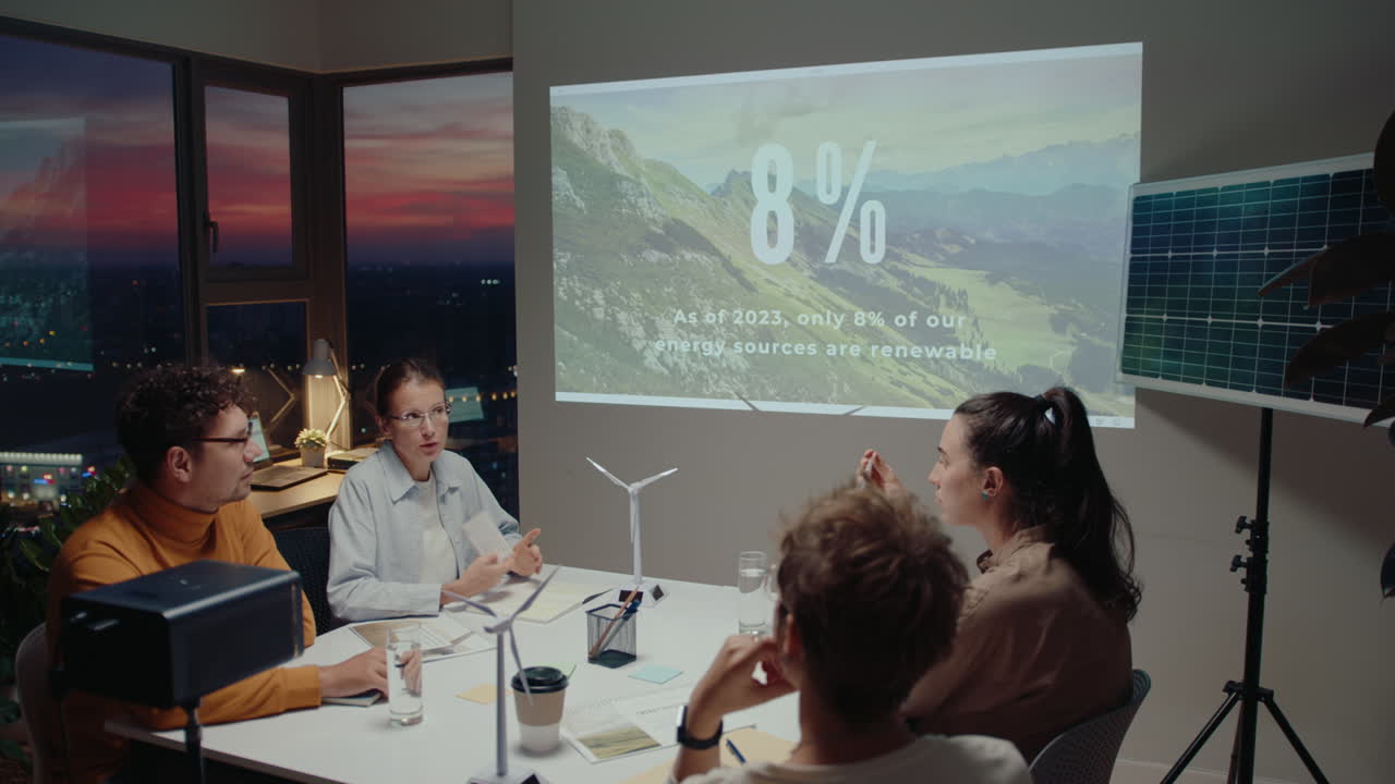 un equipo de colegas discutiendo una presentación sobre fuentes de energía renovables durante una reunión de negocios en la oficina. fotografía de ángulo alto, se ve una hermosa puesta de sol detrás de las ventanas