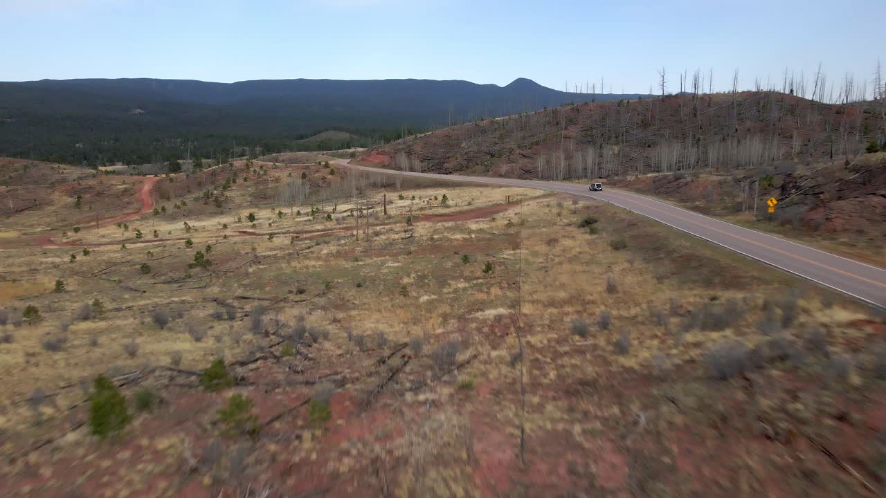 vista de seguimiento aéreo de un solo vehículo que conduce a lo largo de una carretera de montaña remota en el bosque nacional pike, montañas rocosas, colorado