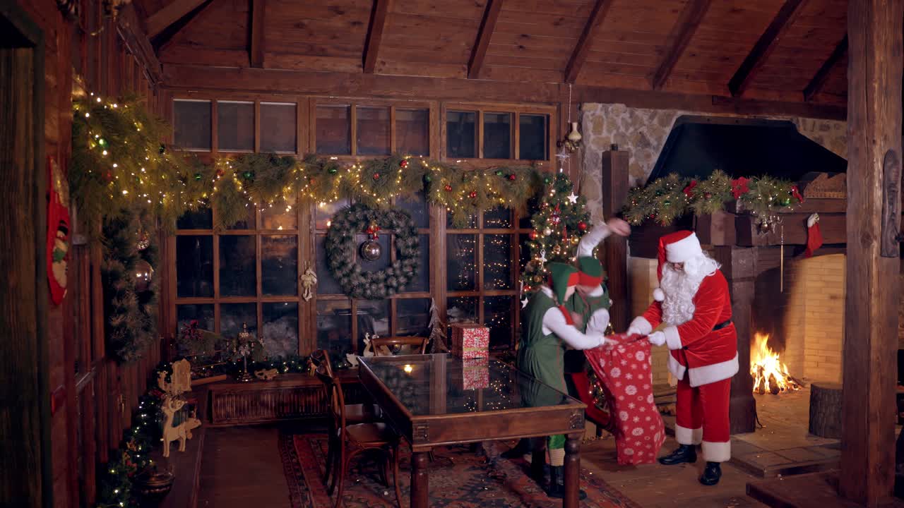 Elves filling up of Santa Claus sack. Santa Claus with elves fills sack with a lot of gifts