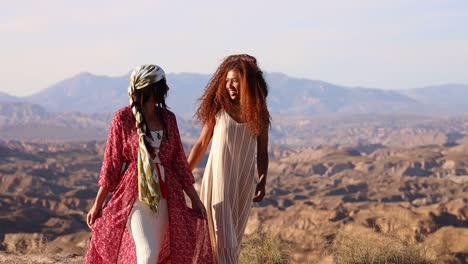 two women walking and smiling in a scenic desert landscape