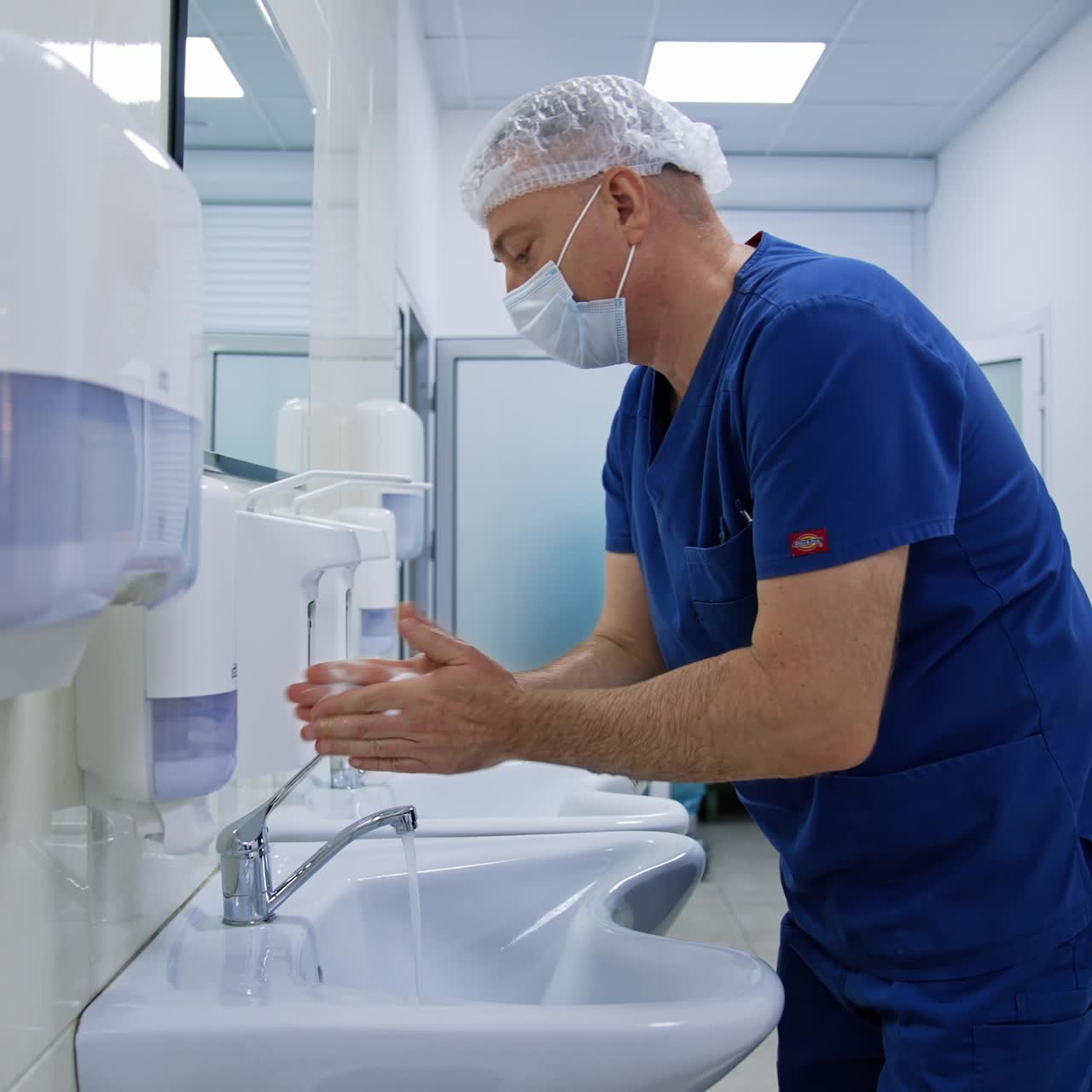 Doctor washing hands in hospital. Side view of professional doctorr washing hands before surgery