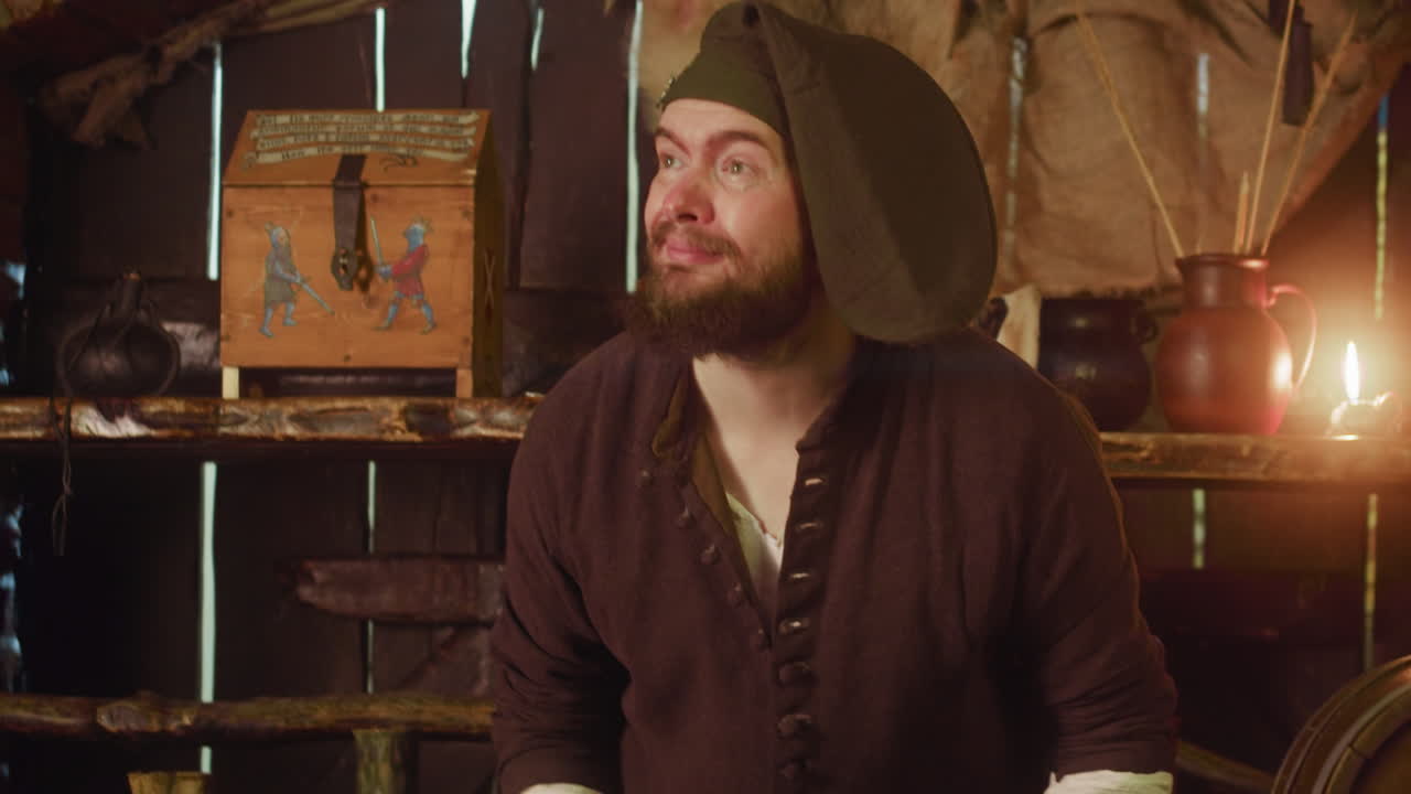 el camarero deja el trabajo para escuchar al cliente en la taberna. un hombre atento con barba toma el pedido de un invitado honorable en una posada medieval. juego de rol de fantasía