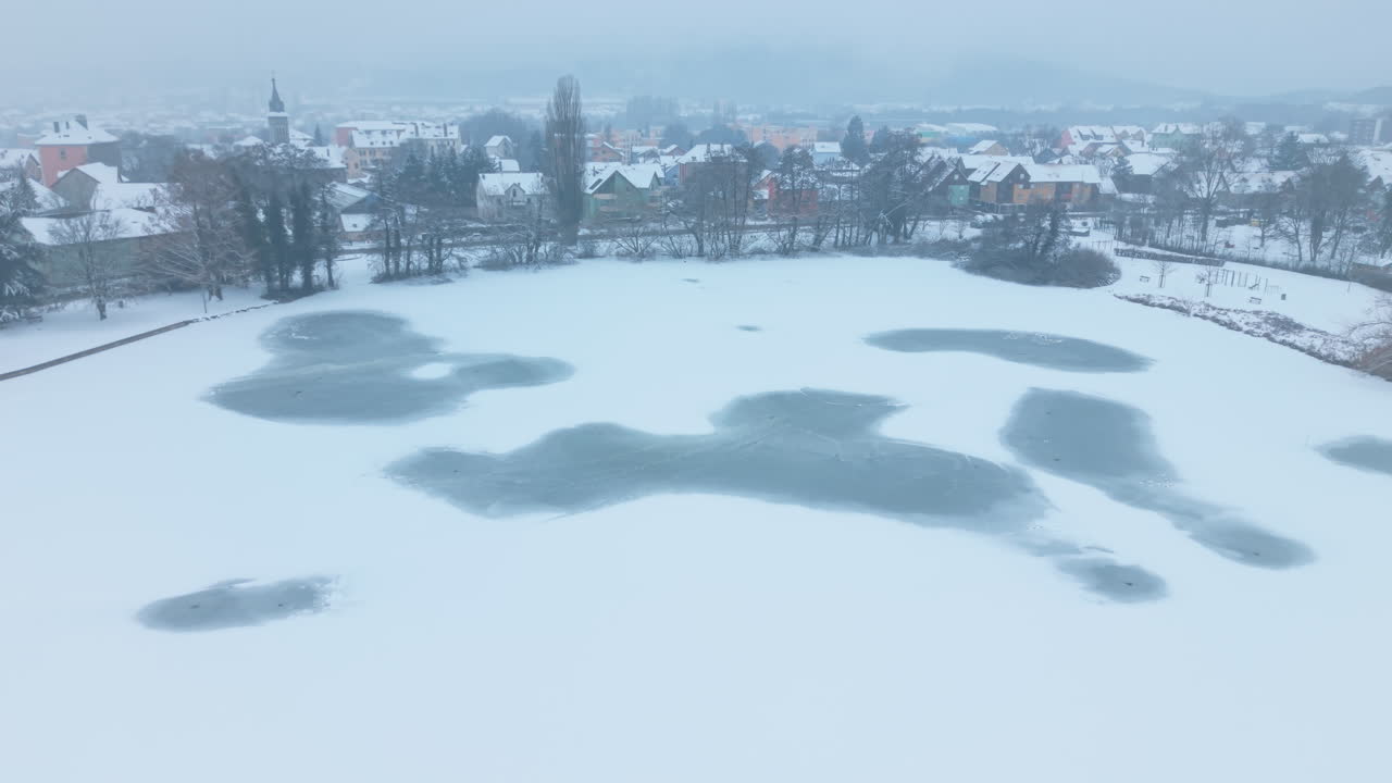 Aerea: ripresa aerea con drone dello stagno ghiacciato di Forges e Belfort sullo sfondo in inverno con la neve, di giorno, in Francia