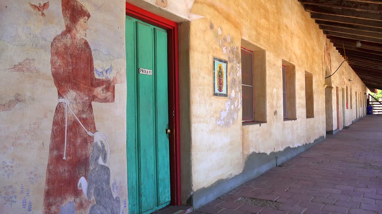los murales se alinean en las paredes de adobe de una misión de california