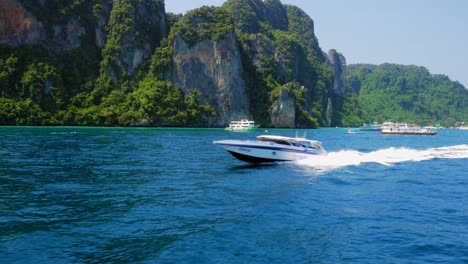toma estática de lancha rápida blanca y azul que se mueve a través del mar azul profundo en la isla ko phi phi en tailandia