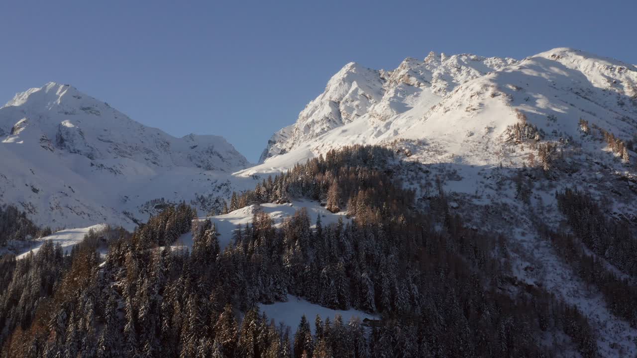 Aerial view of a snow covered mountain ridge with a small chalet on top