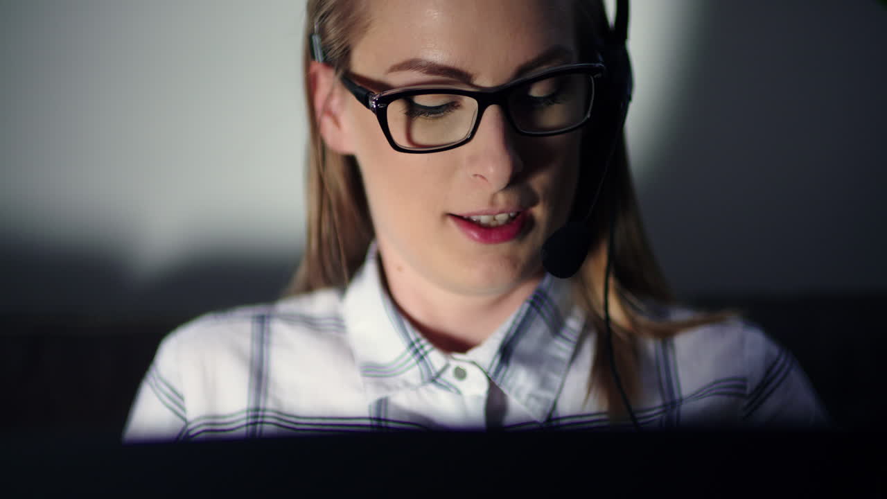 mujer de negocios que usa auriculares y una computadora portátil en la oficina