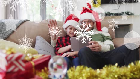 animación de nieve cayendo en navidad sobre feliz padre caucásico con hijo haciendo una videollamada