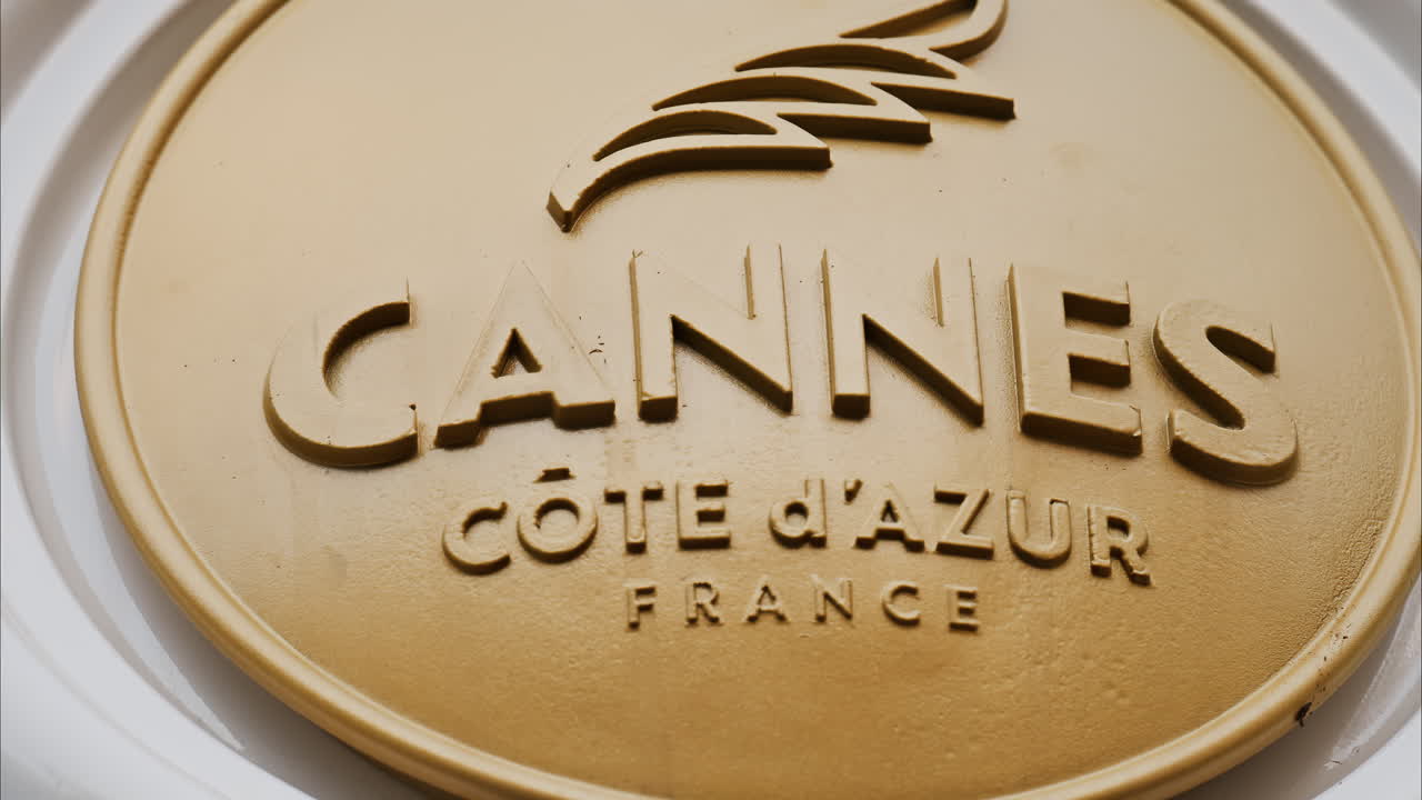 Close up of a white, rotating signboard with the words Cannes in France