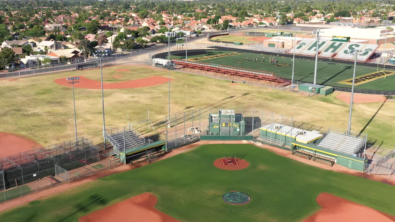 Aerial pull back from an empty baseball diamond, football field in the background.