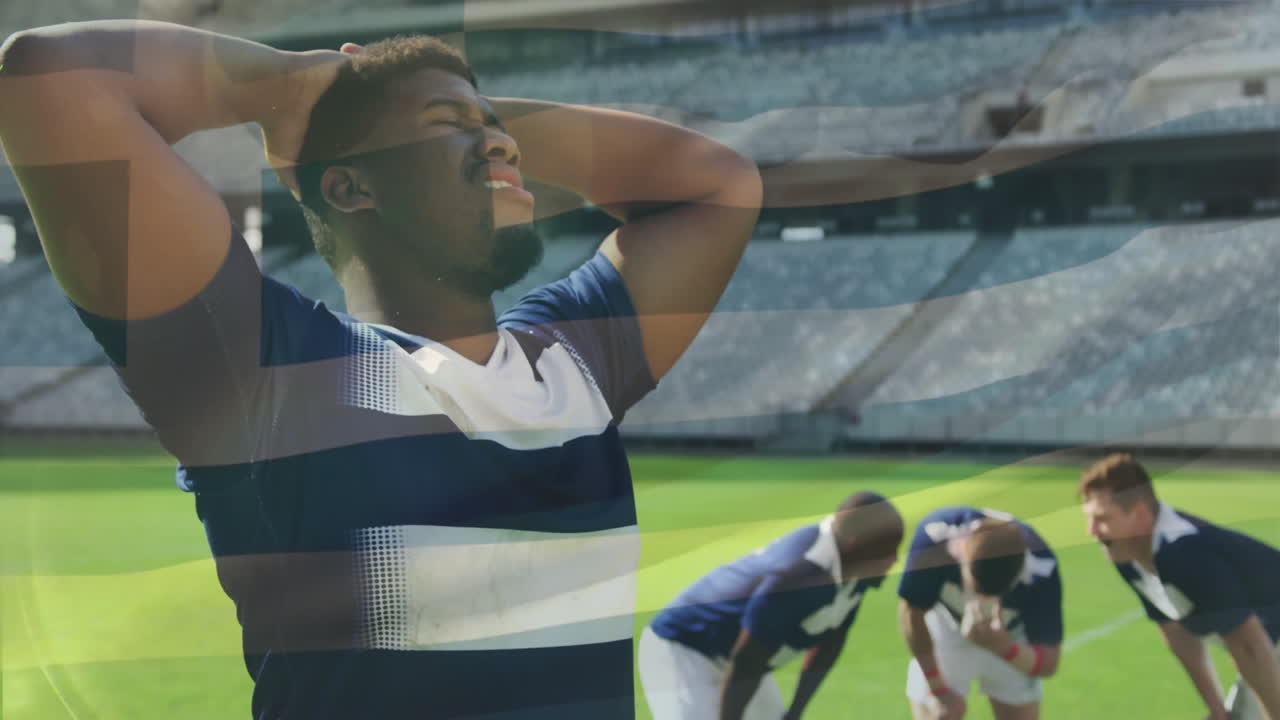In stadium, rugby players resting on field with animation flag overlay