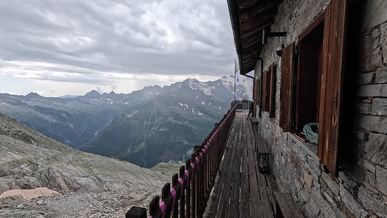 Alpine hut balcony with sweeping mountain views over Alagna Valsesia in the Italian Alps, Piedmont region.