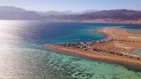 Die-Luftperspektive-Einer-Blauen-Lagune-In-Dahab,-Ägypten,-Bietet-Atemberaubende-Ausblicke-Auf-Das-Angrenzende-Wüstengebiet-Und-Garantiert-Den-Besuchern-Ein-Unvergleichliches-Und-Unvergessliches-Abenteuer