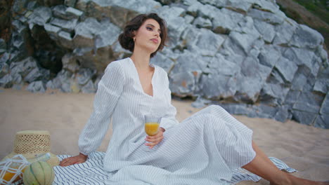 relaxed lady enjoying picnic on ocean beach. elegant romantic model rest shore