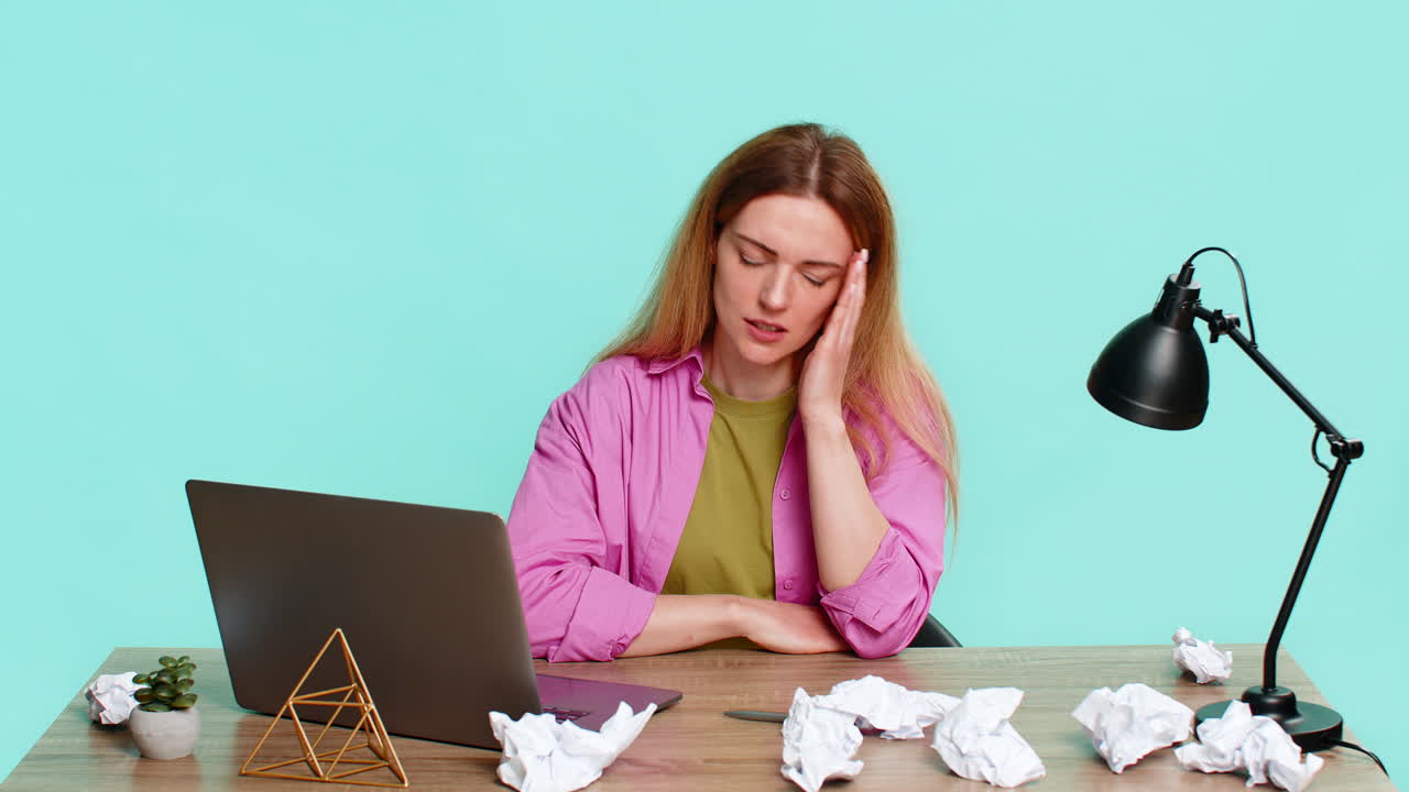 Adult woman sitting at table crumpling paper in frustration after mistake in report failed solution