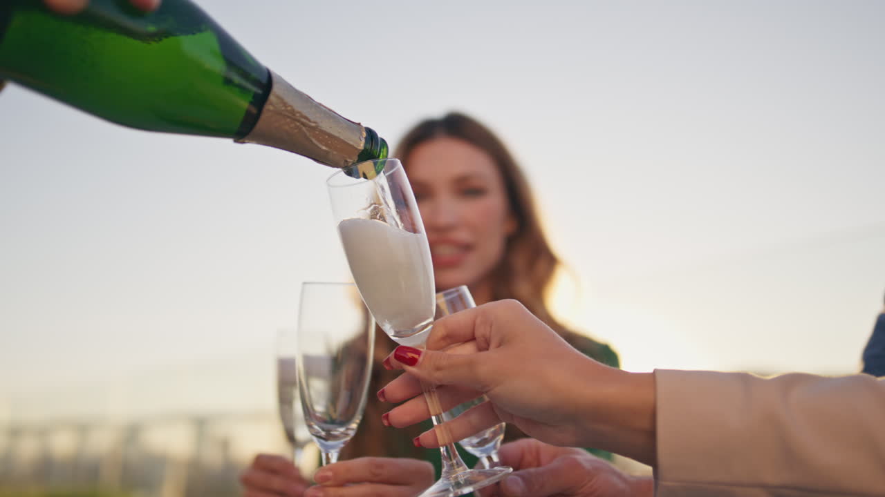 amigos felices llenando vasos de champán en la fiesta de fin de semana en la azotea.
