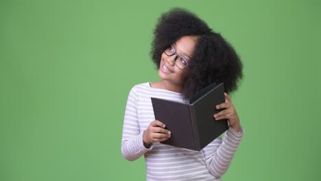 joven chica africana con cabello afro estudiando contra un fondo verde