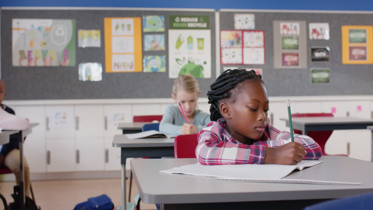 In school, girl writing in notebook at desk, focusing on classroom work
