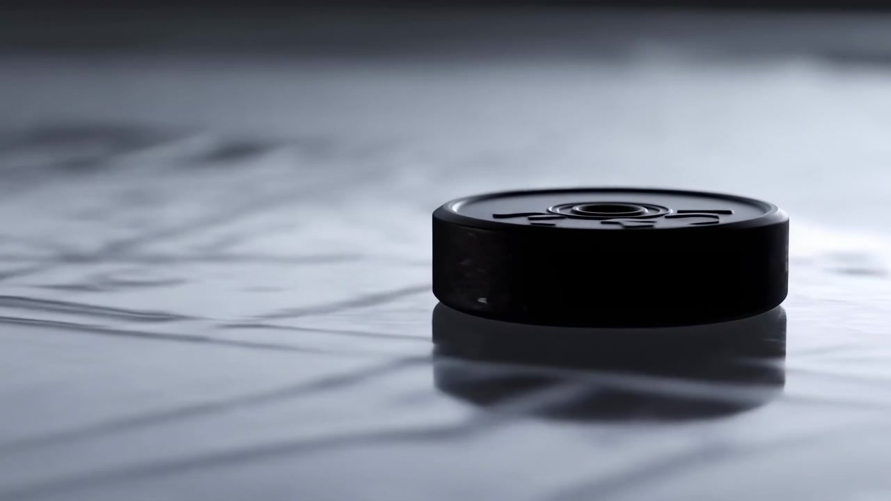 Un objeto cilíndrico negro se exhibe sobre una superficie oscura y texturizada con un patrón de cuadrícula tenue, visto desde una perspectiva cenital. La escena irradia una atmósfera misteriosa y minimalista.