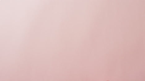 video of woman holding pink heart with copy space on pink background