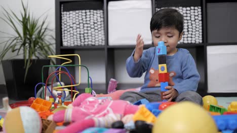 Niño-Mexicano-De-Dos-Años-Jugando-Con-Un-Juguete-Didáctico-En-Un-Salón-Desordenado