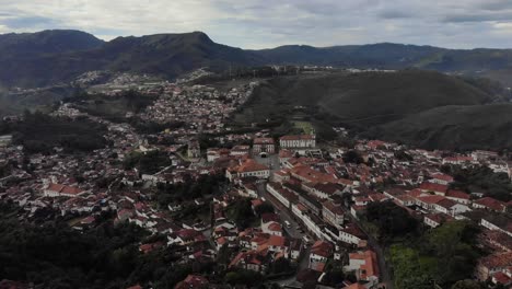 aerial descending tilt showing the historic colonial city centre of ouro preto in minas gerais, brazil, seen from the são sebastião viewpoint with vegetation appearing in the foreground