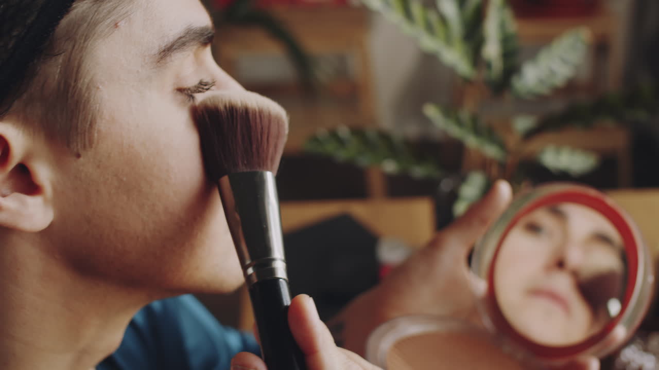 hombre transgénero aplicando polvo para la cara