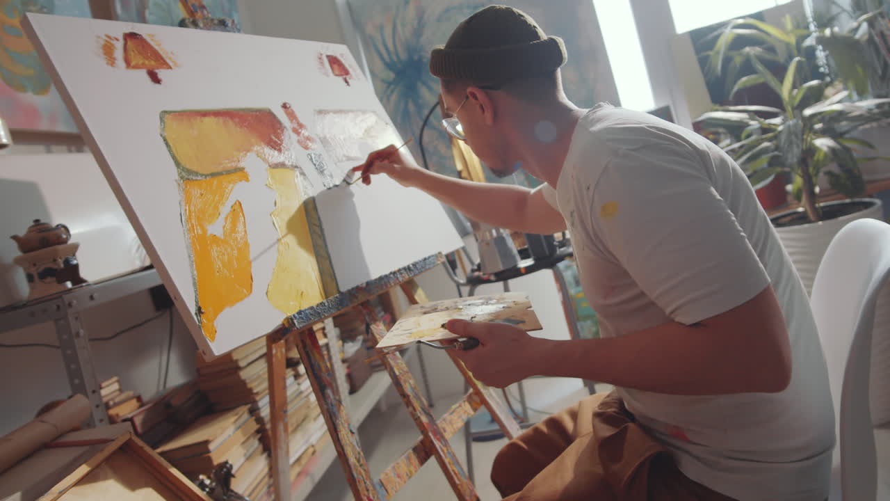 Ung kunstner arbejder på maleri i kunststudie