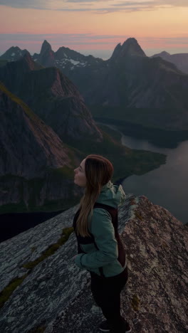 woman enjoying a panoramic mountain and fjord view at sunset