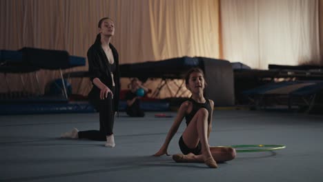 young gymnast training with hoop, coach in background