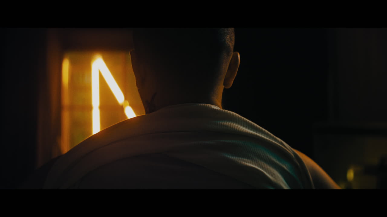 A bald dangerous looking man puts his cloths on