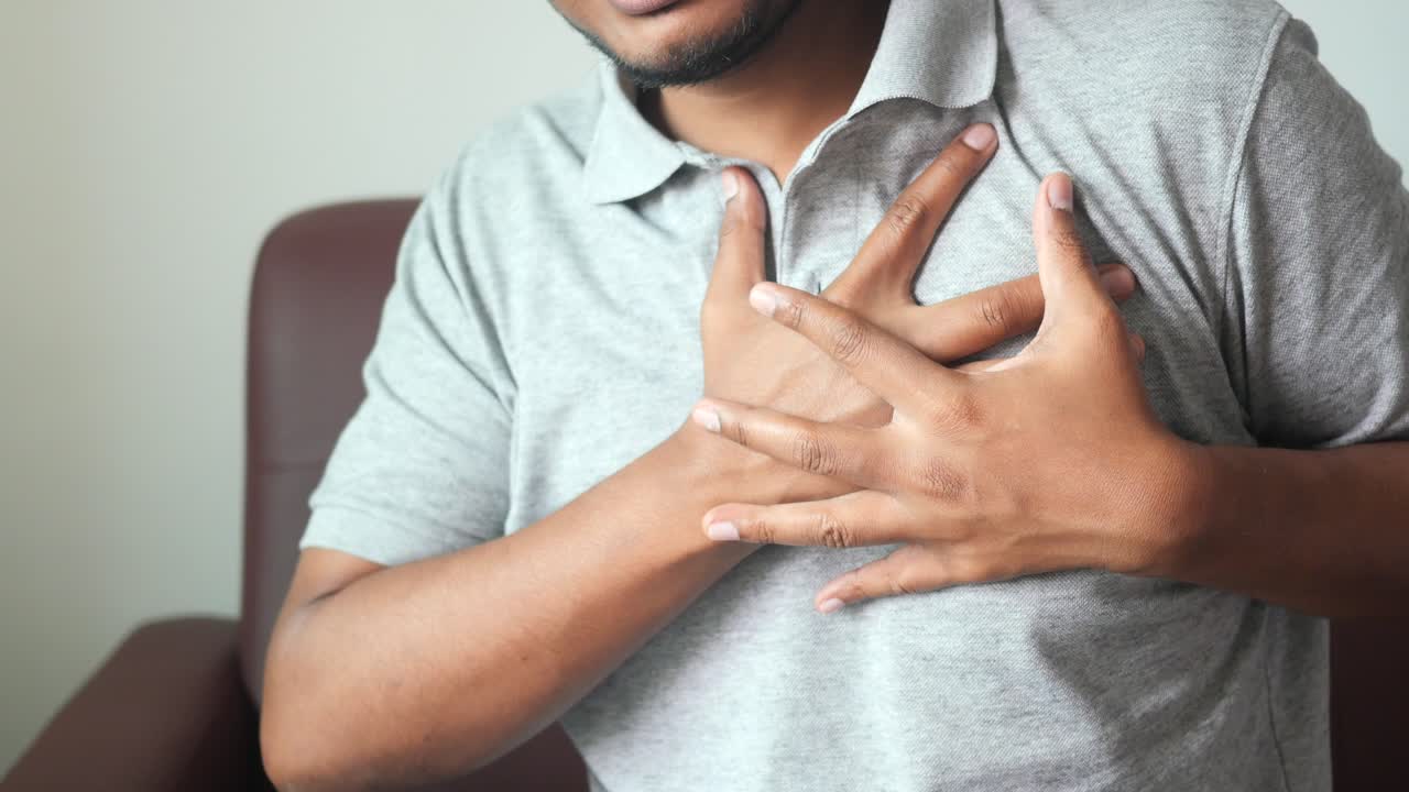 Young man suffering pain in heart and holding chest with hand