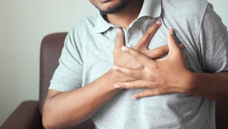 Joven sufre dolor en el corazón y sostiene el pecho con la mano