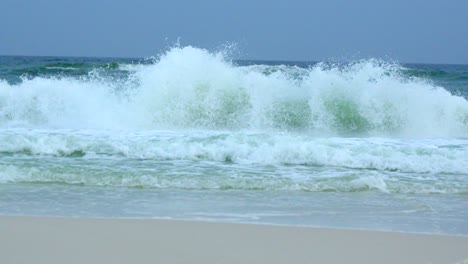 una amplia toma de las olas que se estrellan dramáticamente en cámara lenta en un día tormentoso