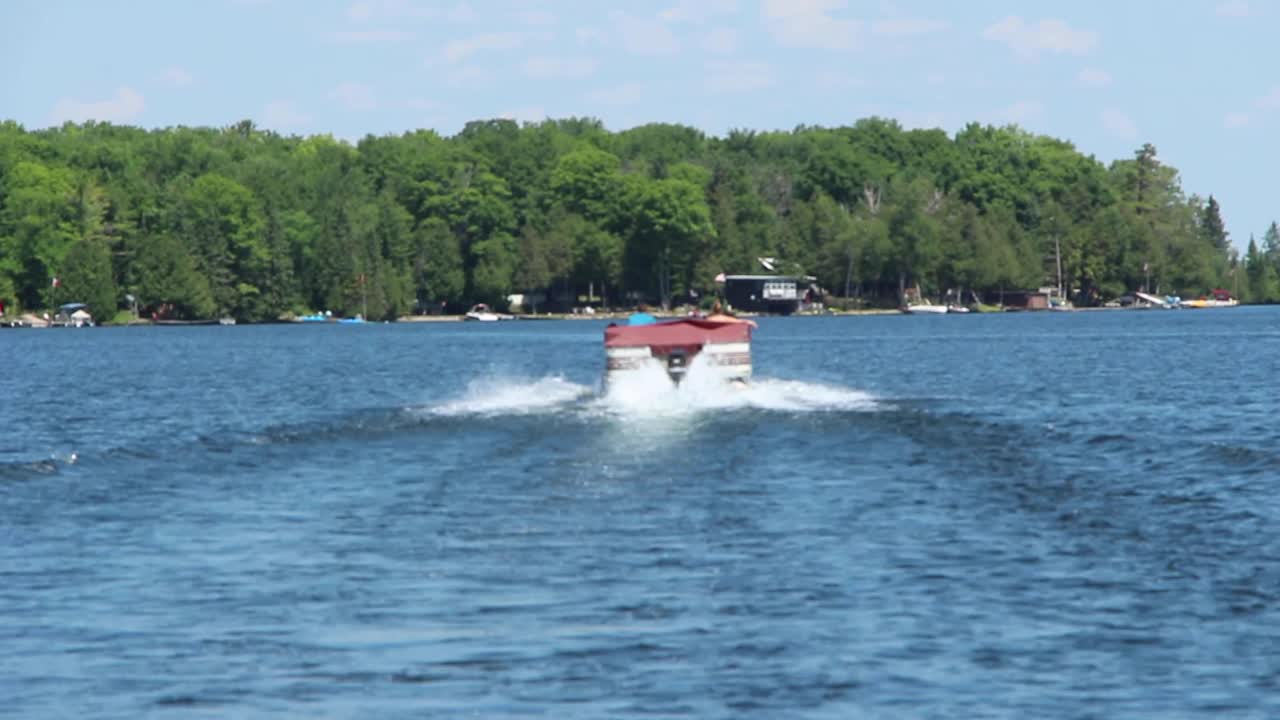 Motor Boat Sailing And Leaving A Wake On The Water In Kawartha Lakes, Ontario, Canada. - wide shot