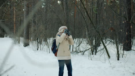 senior woman photographing in a snowy forest