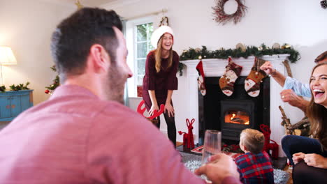 Teenager-Mädchen-Spielt-Pantomime,-Während-Eine-Familie-Aus-Mehreren-Generationen-Zu-Hause-Gemeinsam-Weihnachtsscharaden-Spielt