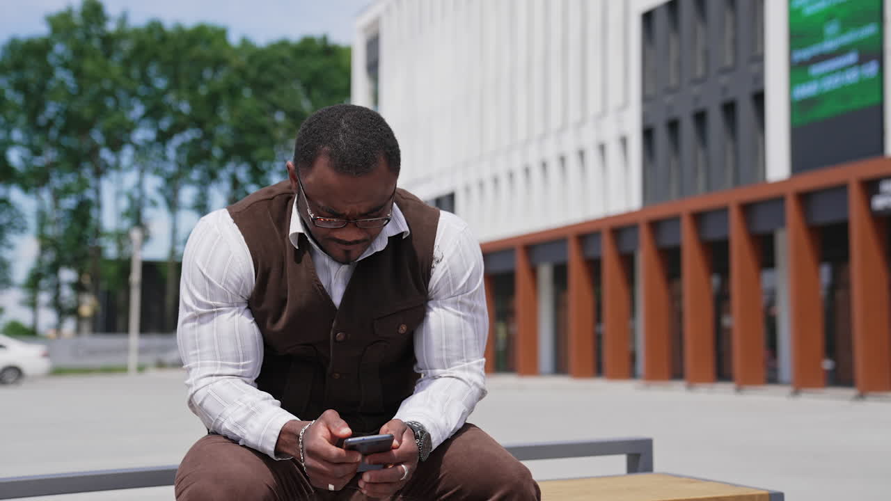 Man in city texting cell phone. Portrait of handsome black young man texting message on mobile phone