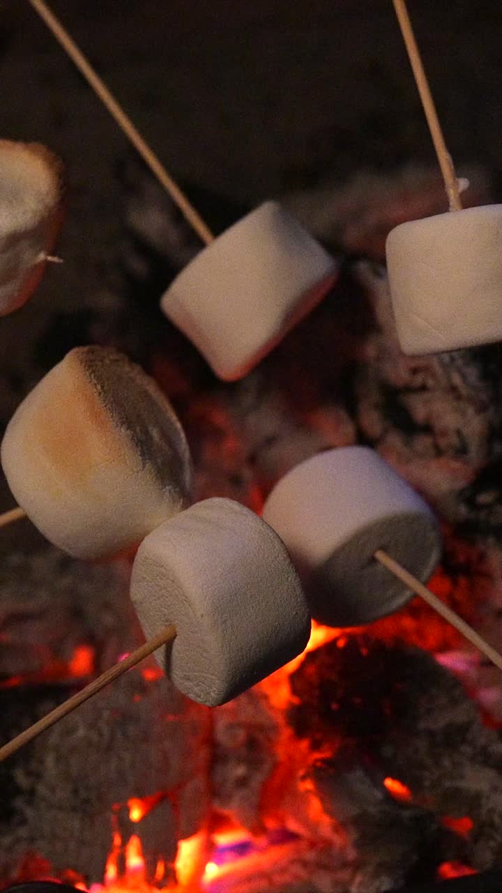 Marshmallow che arrostiscono sulle braci incandescenti di un falò di notte.